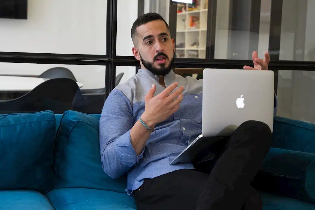 a man sitting on a couch holding a laptop to emphasize the aim of the article: 10 Tips to Lead with Confidence from Day One